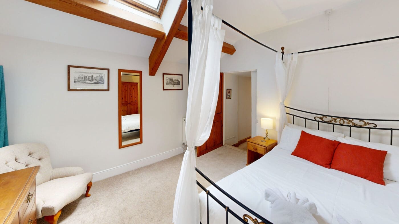 Four poster bed and exposed beam in Y Stabl holiday cottage
